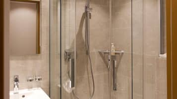 Een badkamer met een douche met glazen wand, een wastafel met spiegel en een zeepdispenser.