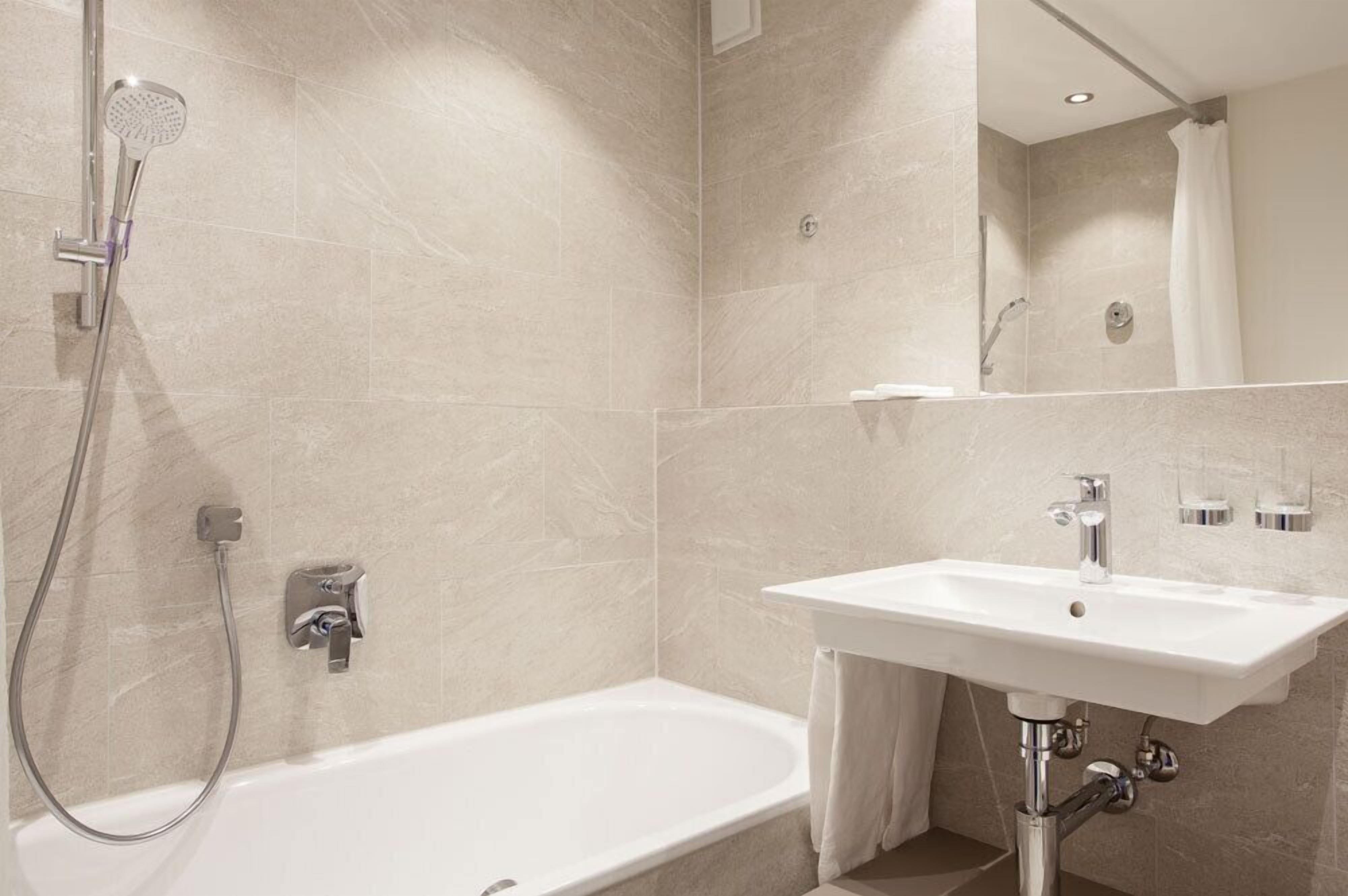 A modern bathroom with a bathtub, a shower, and a sink.