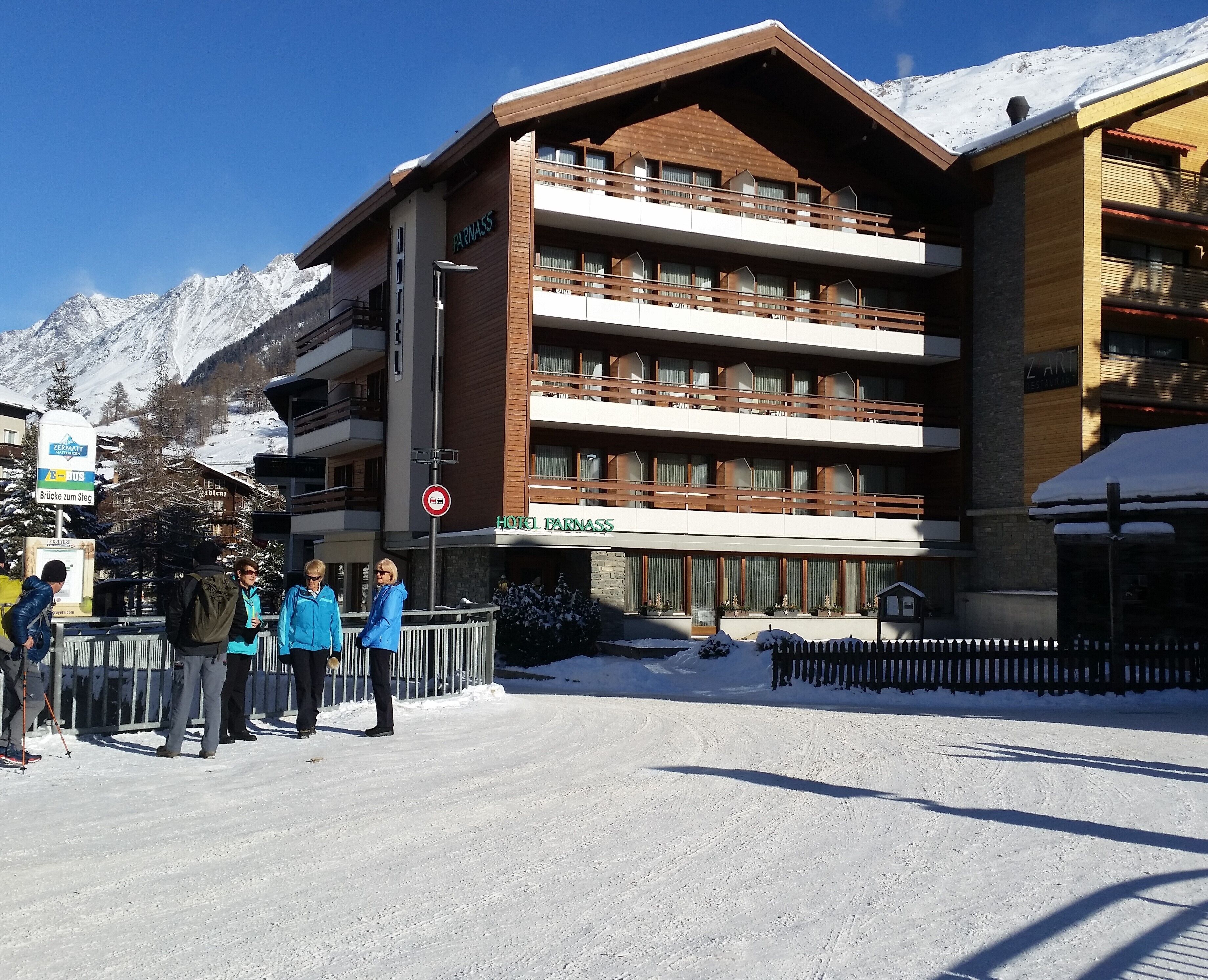 A multi-story hotel with balconies and a ski resort backdrop.