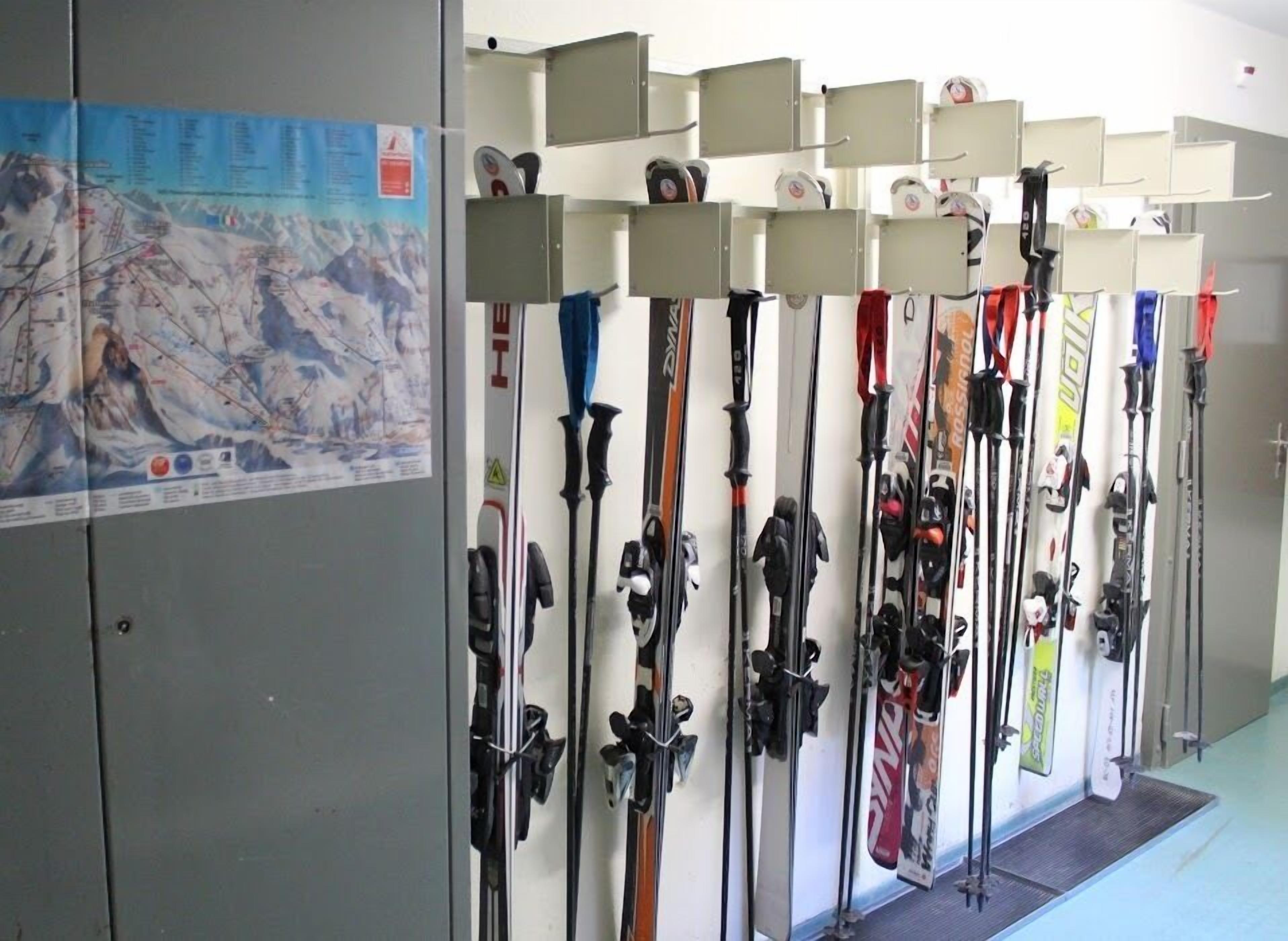 Un magasin de location de skis où l'on peut trouver de nombreux paires de skis et de bâtons de ski, rangés en rangées.