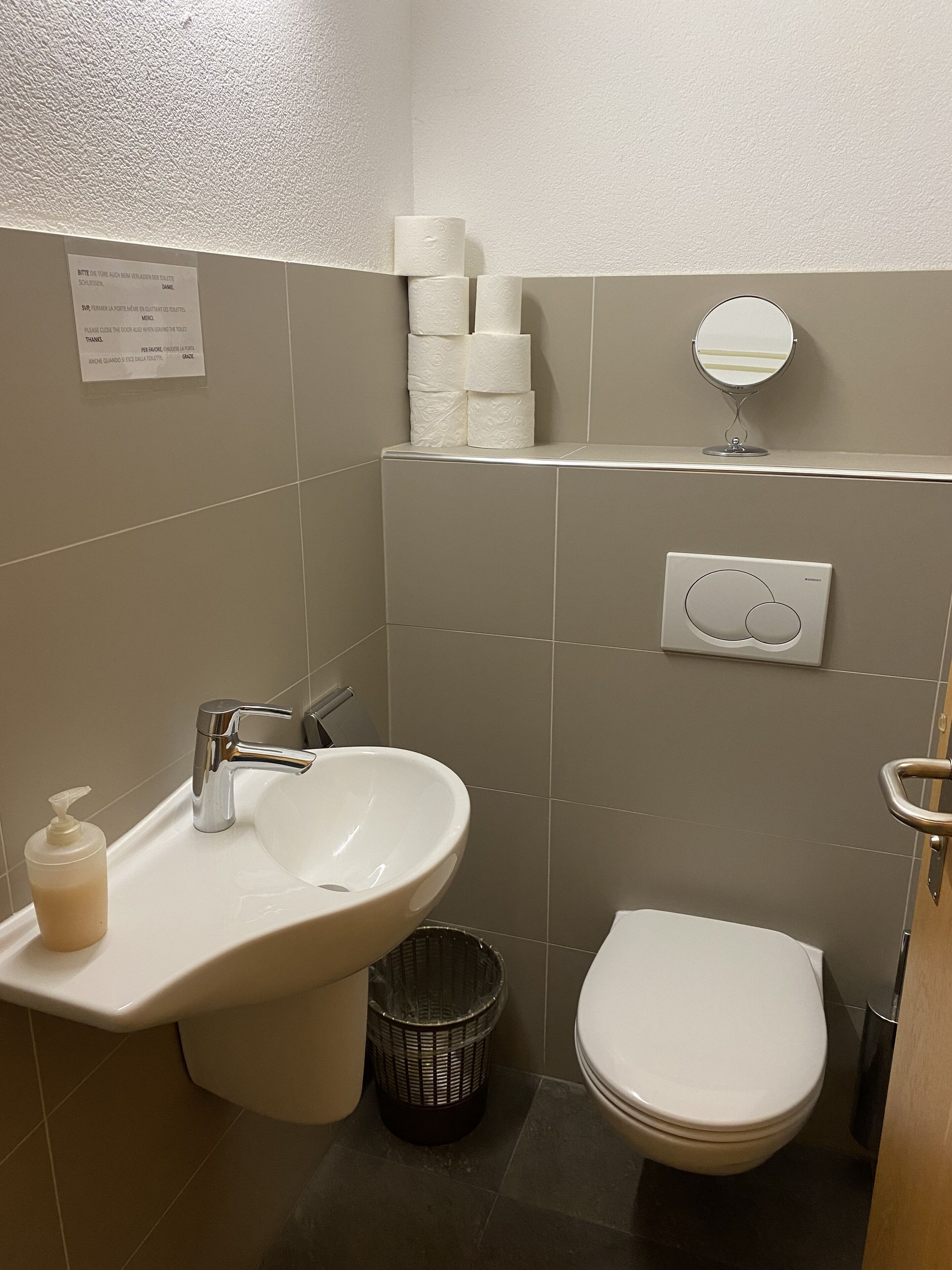 A bathroom with a sink, toilet, and a mirror.