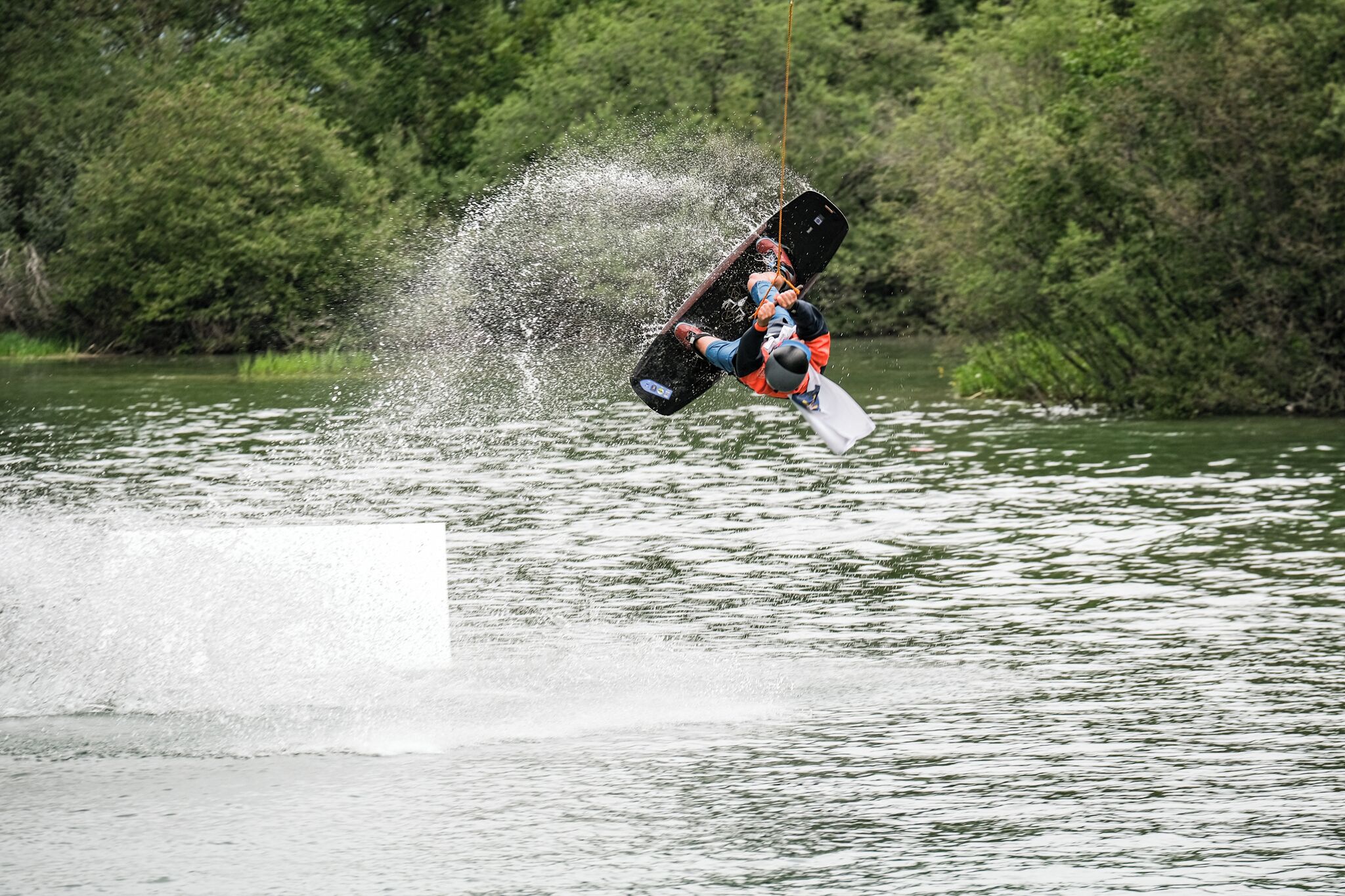 Iemand voert een wakeboardtruc uit boven het water.