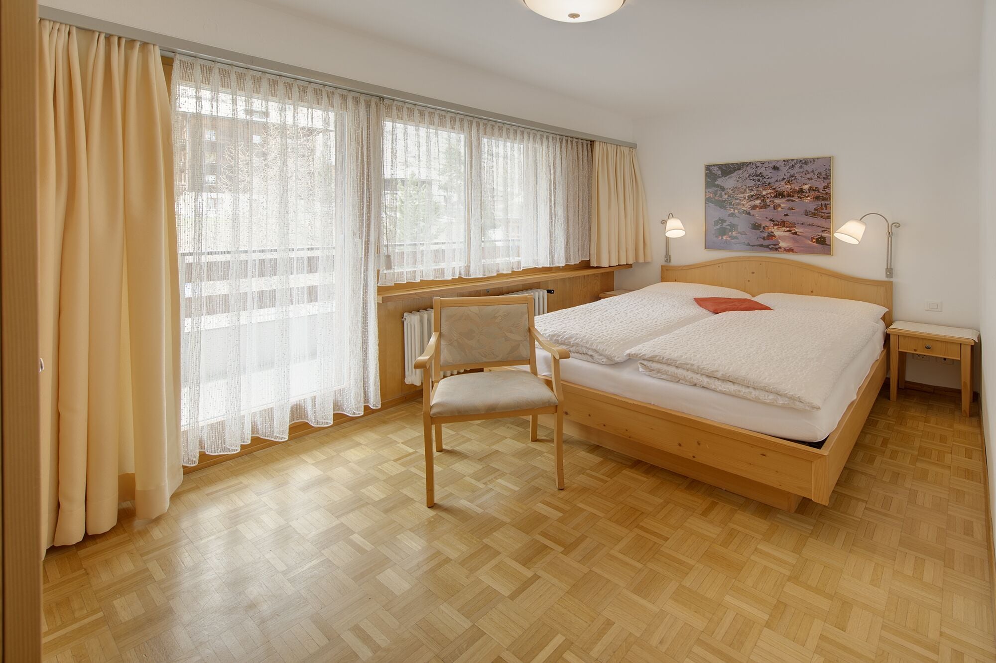 Un dormitorio con una cama de madera, una silla, un radiador y un cuadro en la pared.