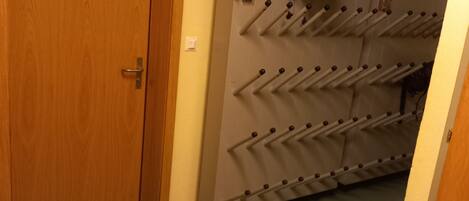 A room with a wooden door, a shoe rack with multiple pairs of shoes, and a chair.