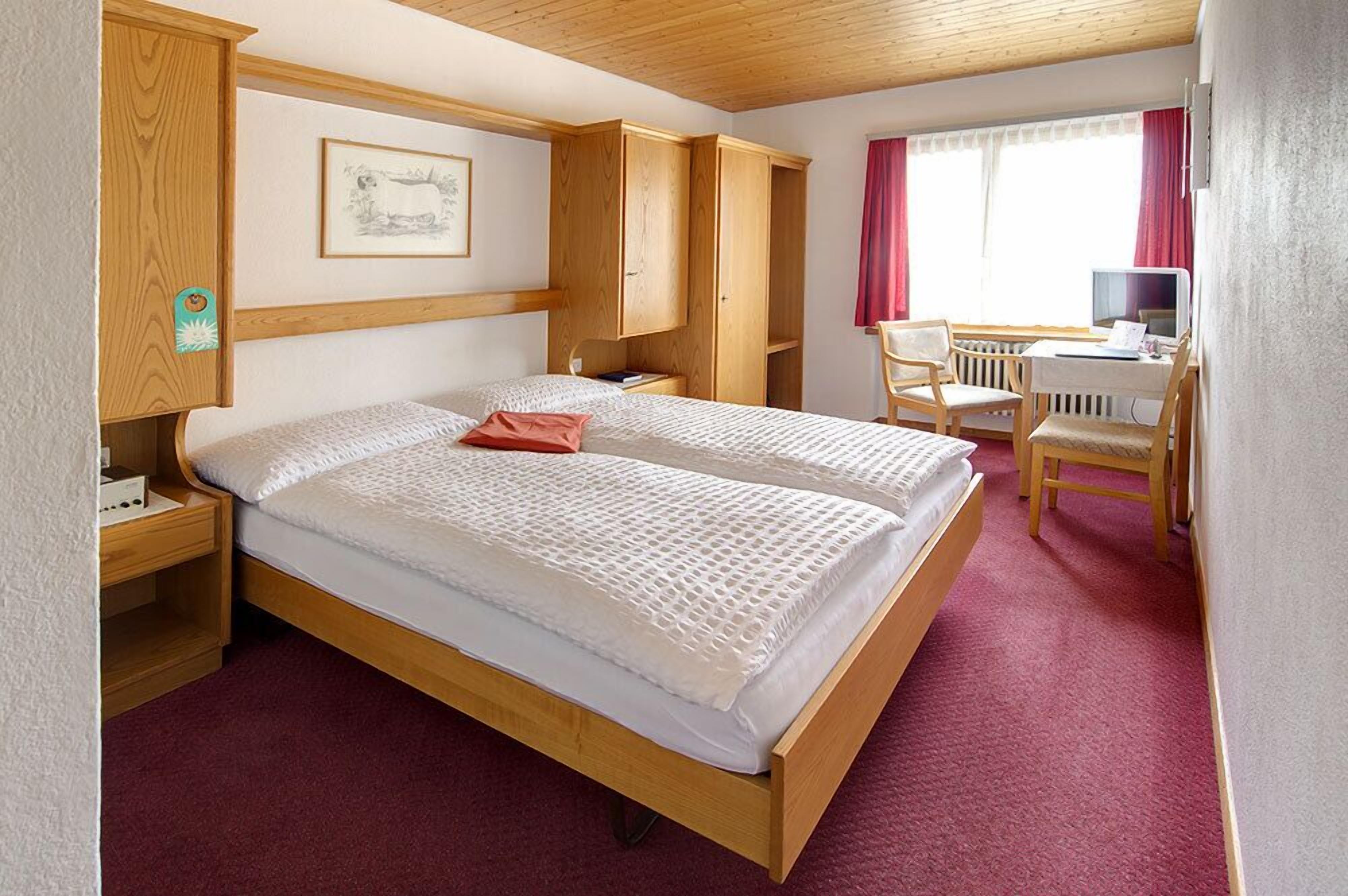 Un dormitorio con una cama grande, un armario de madera, un escritorio con silla y un radiador.