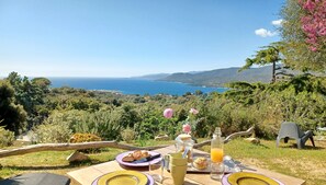A table set outdoors with a view of the sea and hills. - U Castellu (Viggianello)