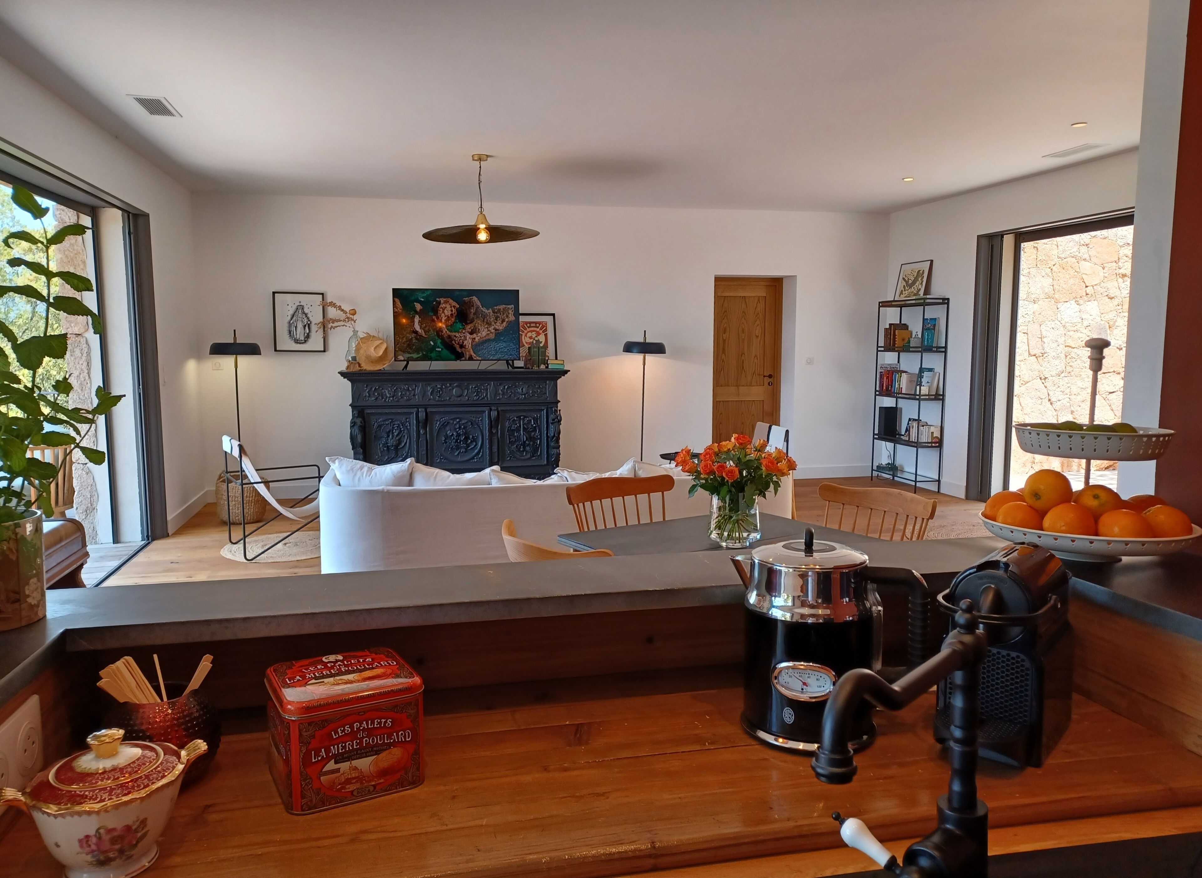 Ein modernes Wohnzimmer mit Sofa, Couchtisch, einem dekorativen Schrank, einem Bücherregal und einem Fenster mit Blick.