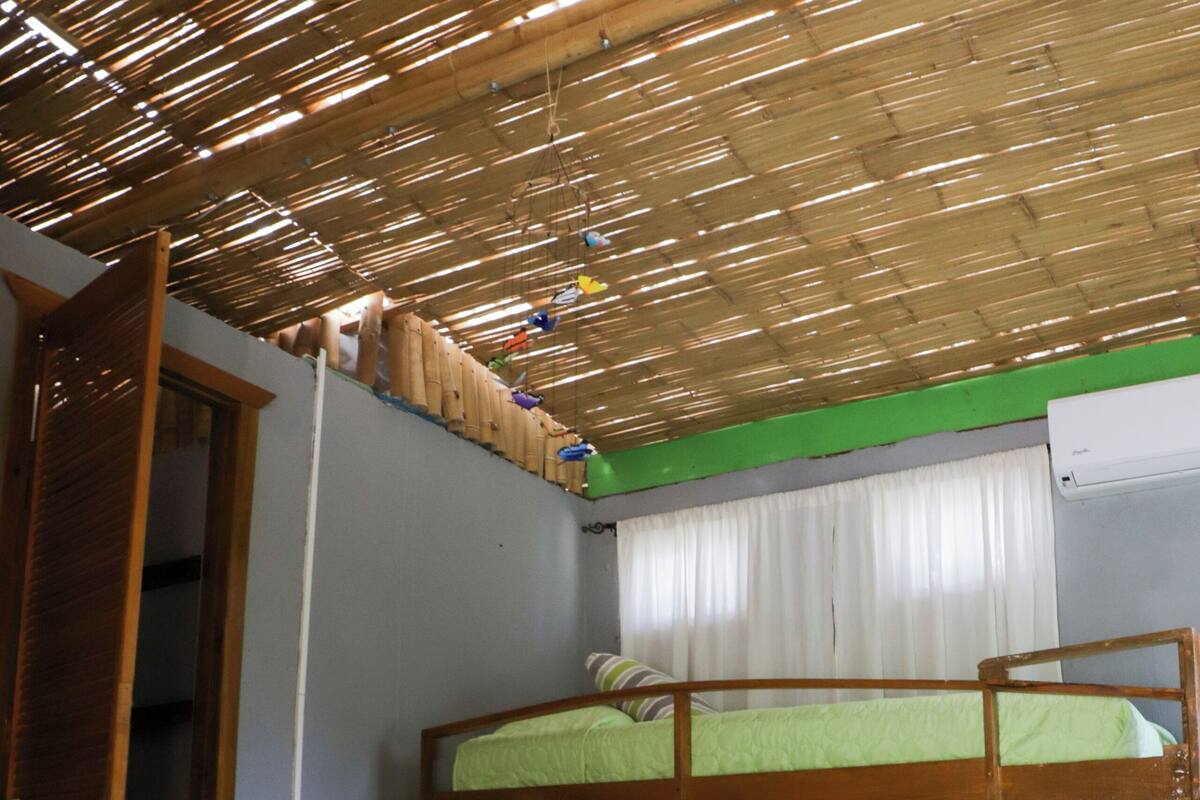 Ein Zimmer mit Etagenbetten, einem Sessel und einem Bett mit gelber Decke.