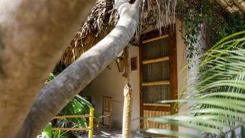 A rustic thatched-roof structure with a wooden door and a small wooden chair inside.