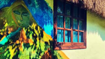 Une fresque colorée orne le mur d’un bâtiment doté d’une fenêtre surmontée d’un toit de chaume.