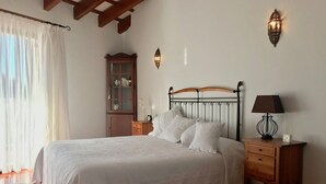 A bedroom with a bed, nightstands, a wooden cabinet, and wall sconces. - VILLA VICTORIA (SON BLANC) (Son Blanc)