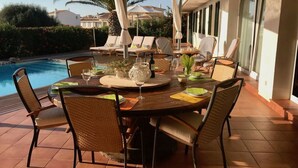 An outdoor dining area with a pool, chairs, and umbrellas. - VILLA VICTORIA (SON BLANC) (Son Blanc)