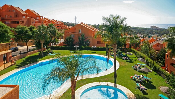 Ein Resort mit großem Pool, Palmen und Liegestühlen.