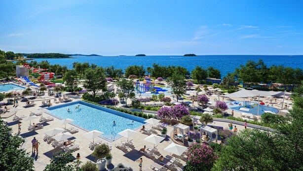 Un resort con varias piscinas, tumbonas y vistas al mar.
