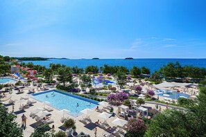 Resort com várias piscinas, espreguiçadeiras e vista para o mar.