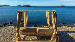 Vista de una playa con una sombrilla y un banco.