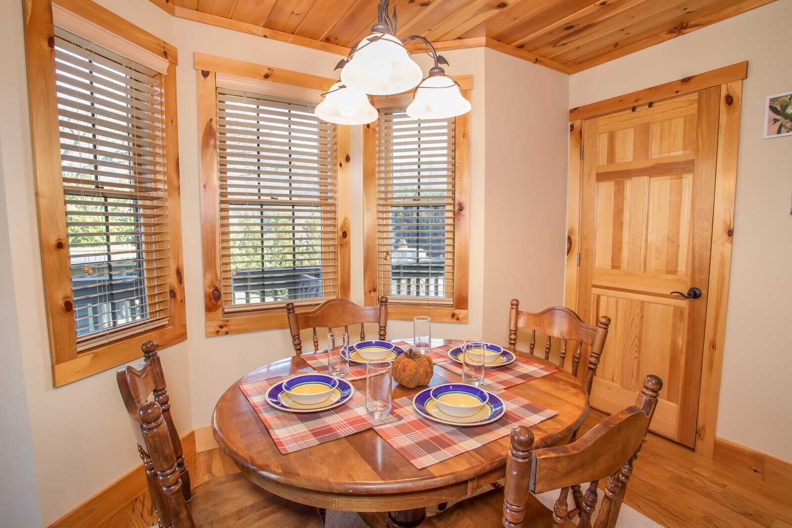 Una mesa de madera para comer con cuatro sillas, un mantel a cuadros y un tazón de sopa.