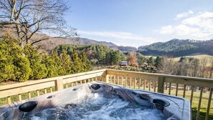 Een hottub op een houten terras met uitzicht op een bergachtig landschap.