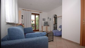 A living room with a sofa, a TV, and a small table. - Two-room apartment Alex 1, 2 minutes drive from the beach (Marina di Campo)