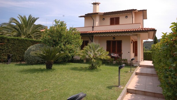 A two-story house with a tiled roof, a chimney, and a small porch. - Two-room apartment Alex 1, 2 minutes drive from the beach (Marina di Campo)