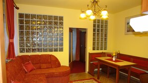 A compact living space with a sofa, a dining table, and a bench. - HoldLux Apartmanok (Sarvar)