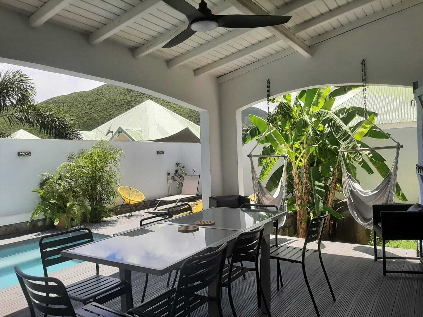 Un patio con piscina, mobiliario exterior y una hamaca.