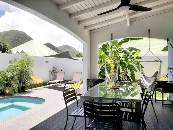A modern outdoor dining area with a glass table, black chairs, and a pool. - Casa Del Tamaris,10 mn walk to Orient Bay beach, swimming pool, tropical garden (Saint Martin)