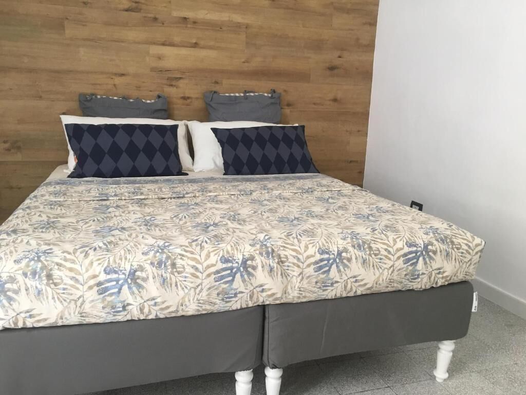 Una cama con una colcha de estampado floral, dos almohadas con un diseño de rombos y un cabecero de madera.