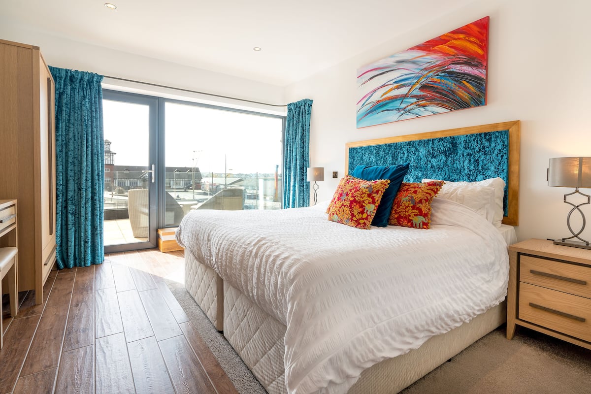 Une chambre d’hôtel avec un grand lit, un bureau, une chaise et une vue sur la ville par la fenêtre.