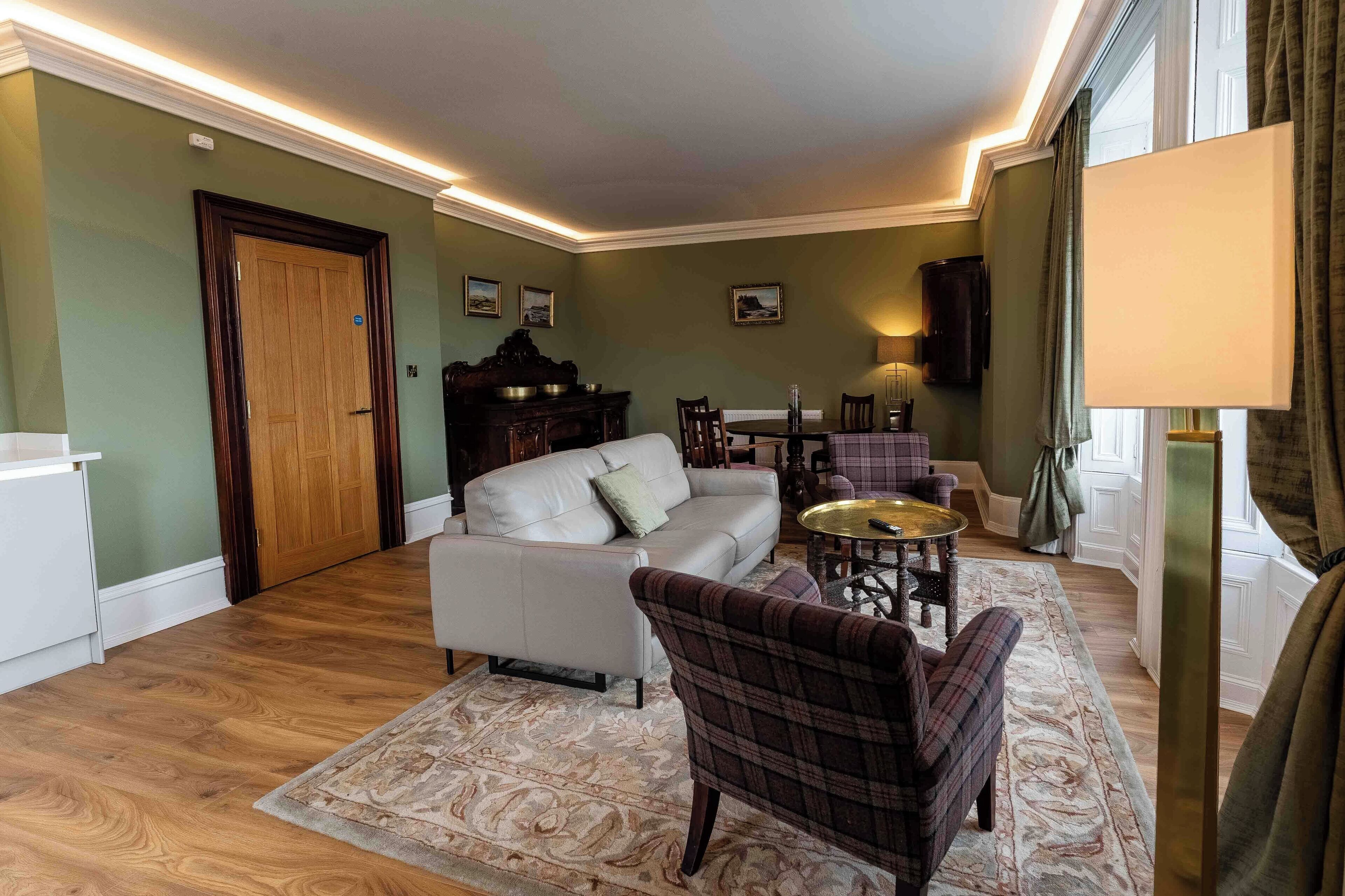Una sala de estar con sofá, sillón, mesa de centro y mesa de comedor con sillas.