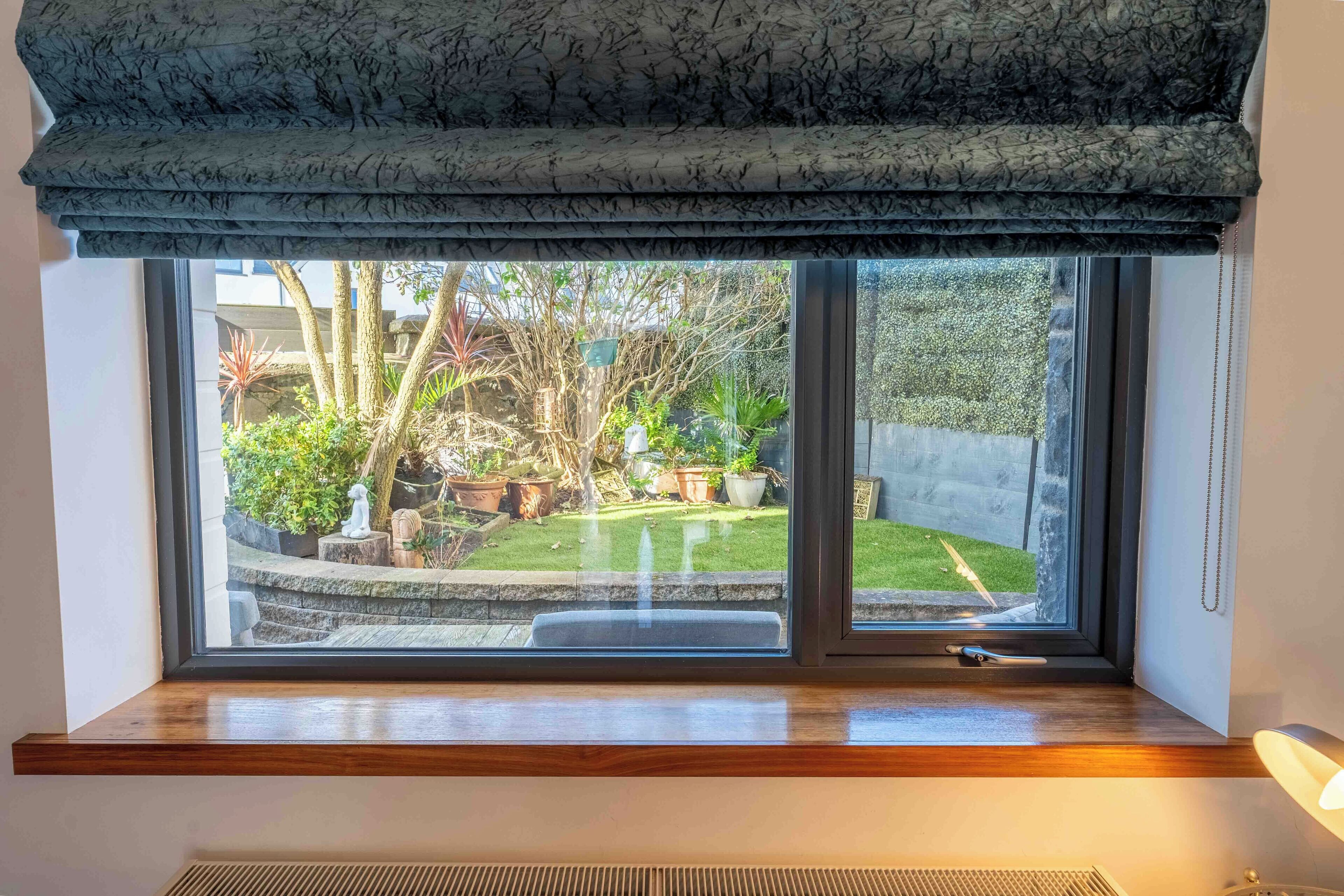 A window with a view of a garden and a statue.