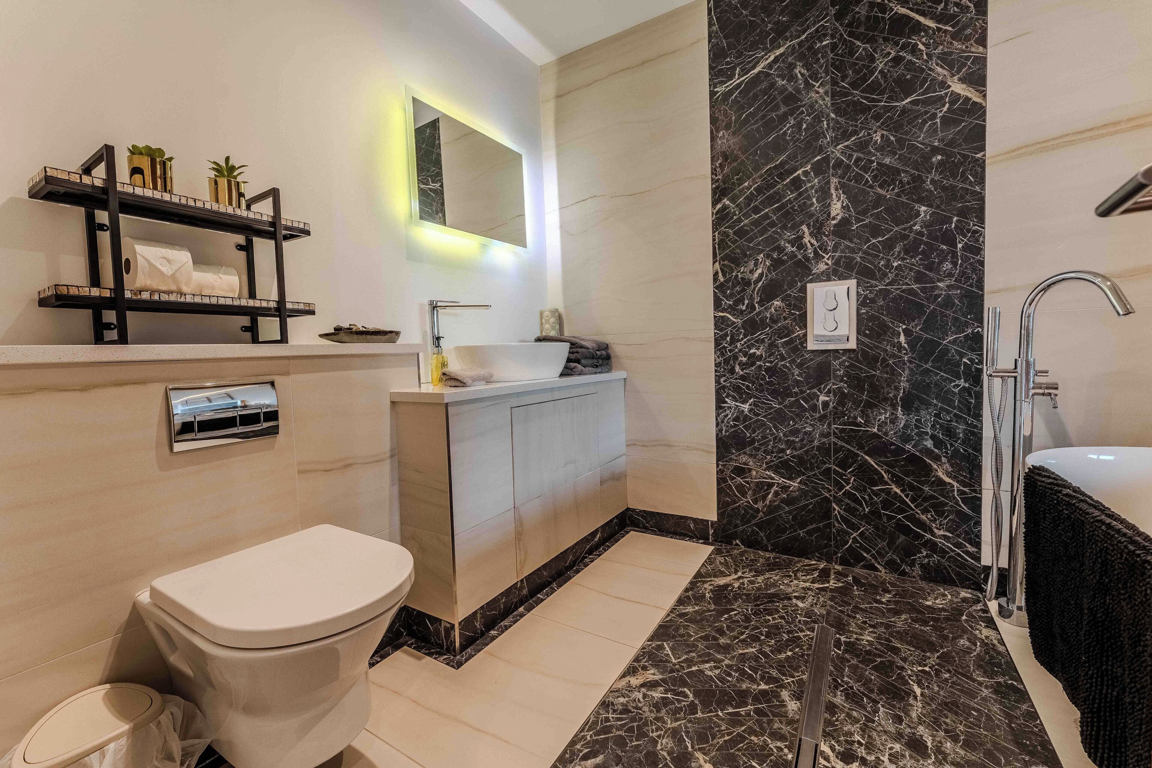 A modern bathroom with a marble floor, a toilet, a sink with a vanity, and a shower area.