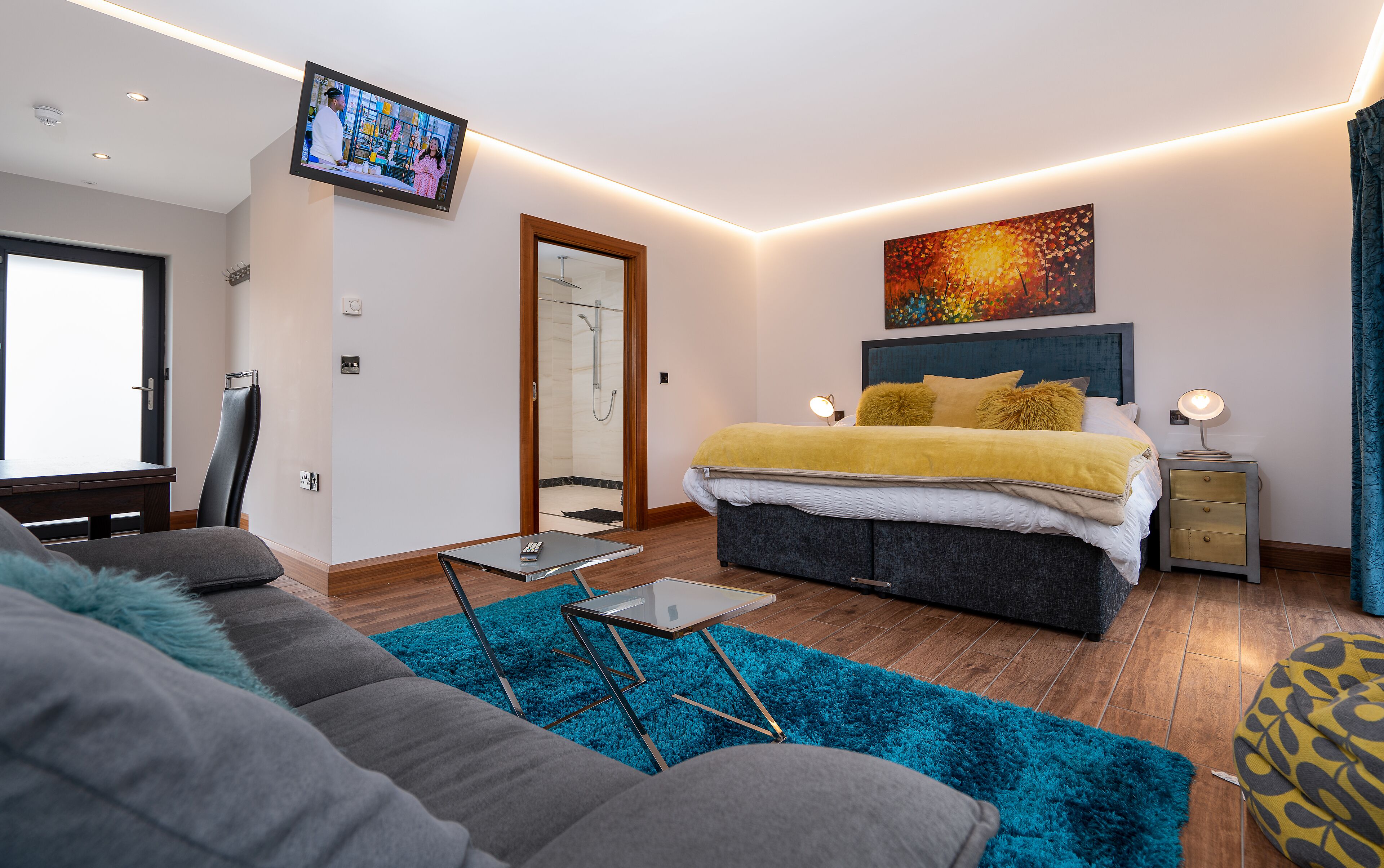 A modern bedroom with a bed, bedside table, and a TV mounted on the wall.