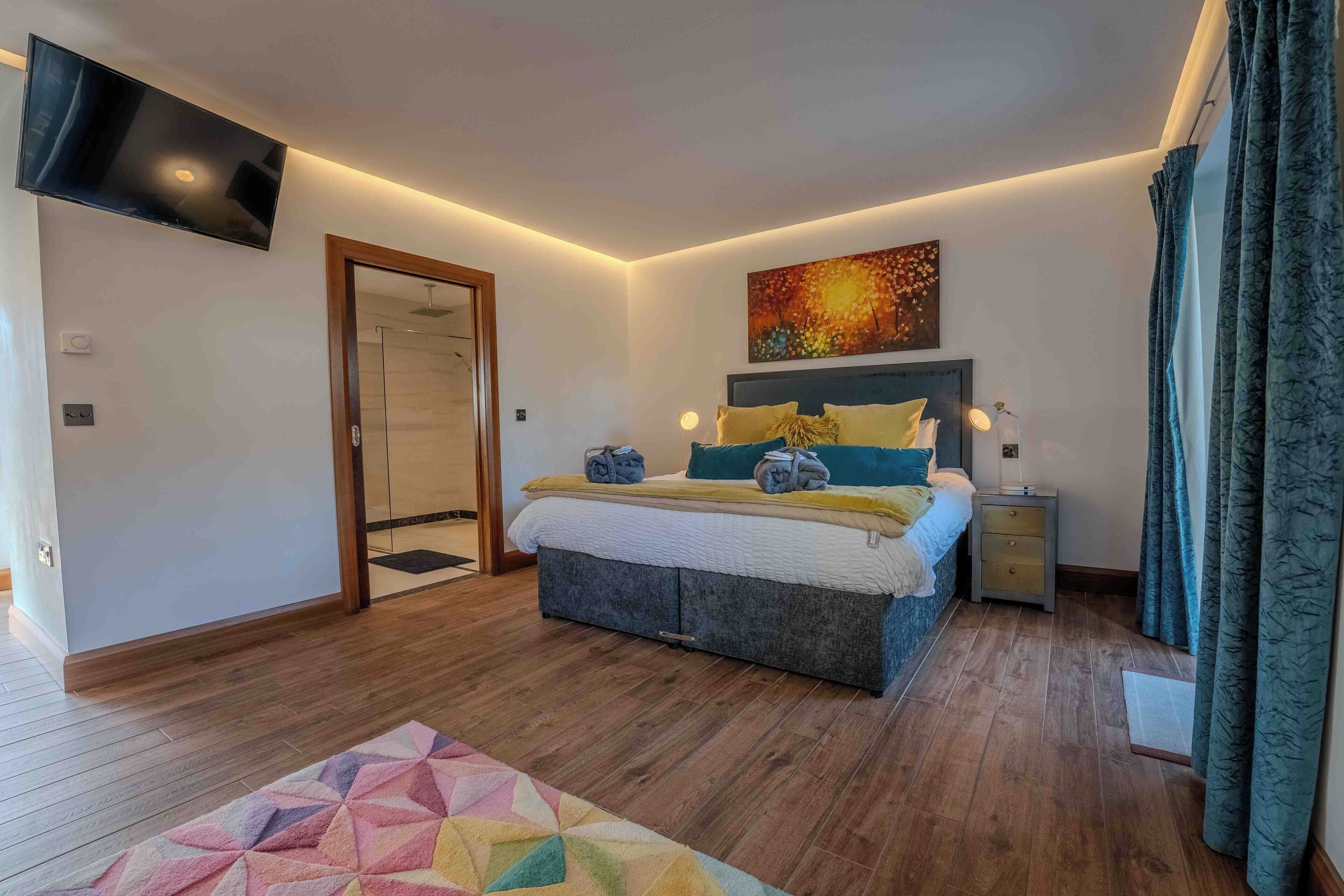 A modern bedroom with a bed, bedside tables, a TV, and a painting on the wall.