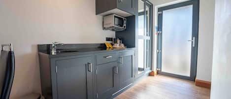 A modern kitchen with dark cabinets, a microwave, and a sink.