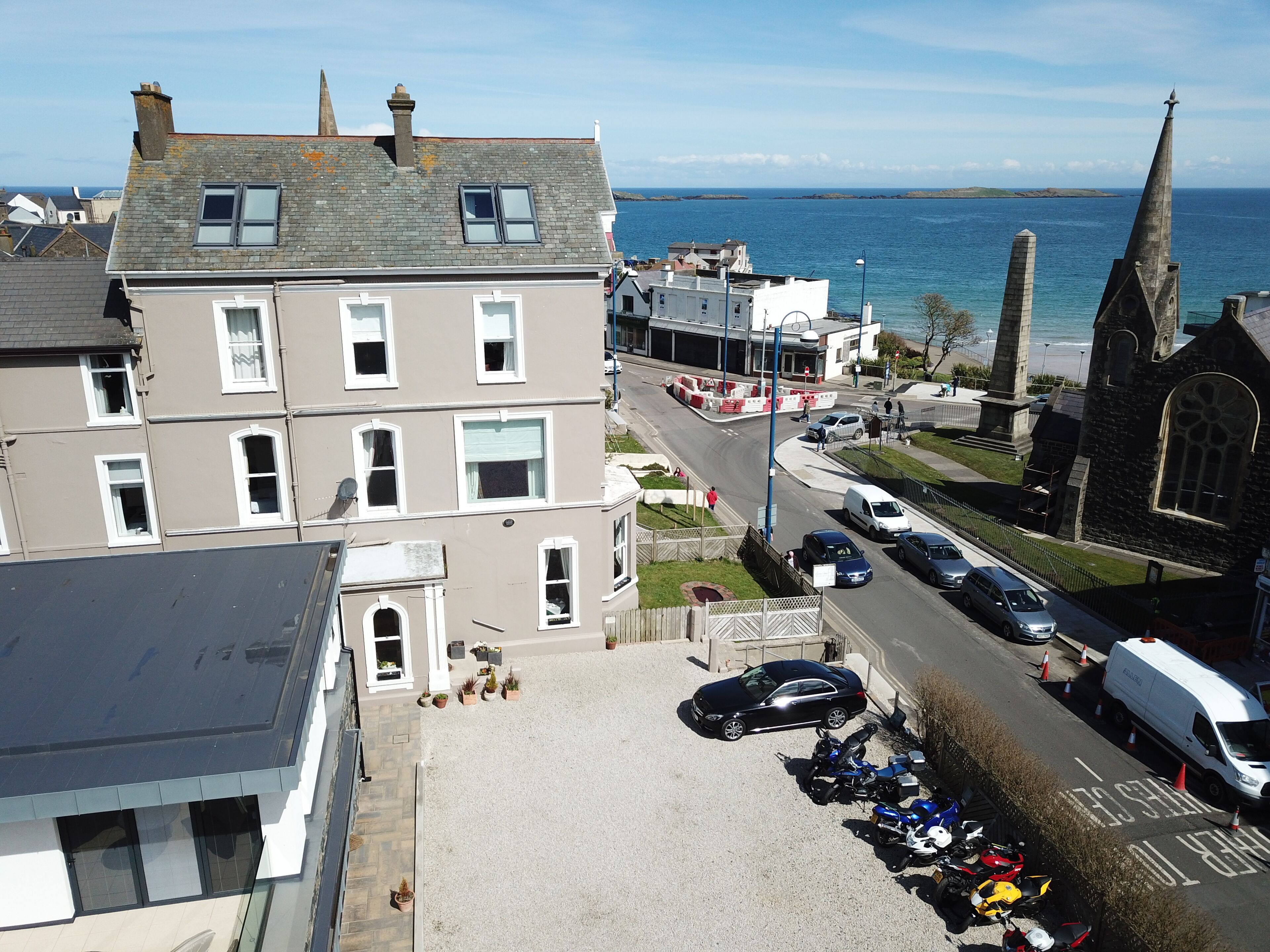 A coastal town with a prominent church, parked cars, and a clear view of the sea.