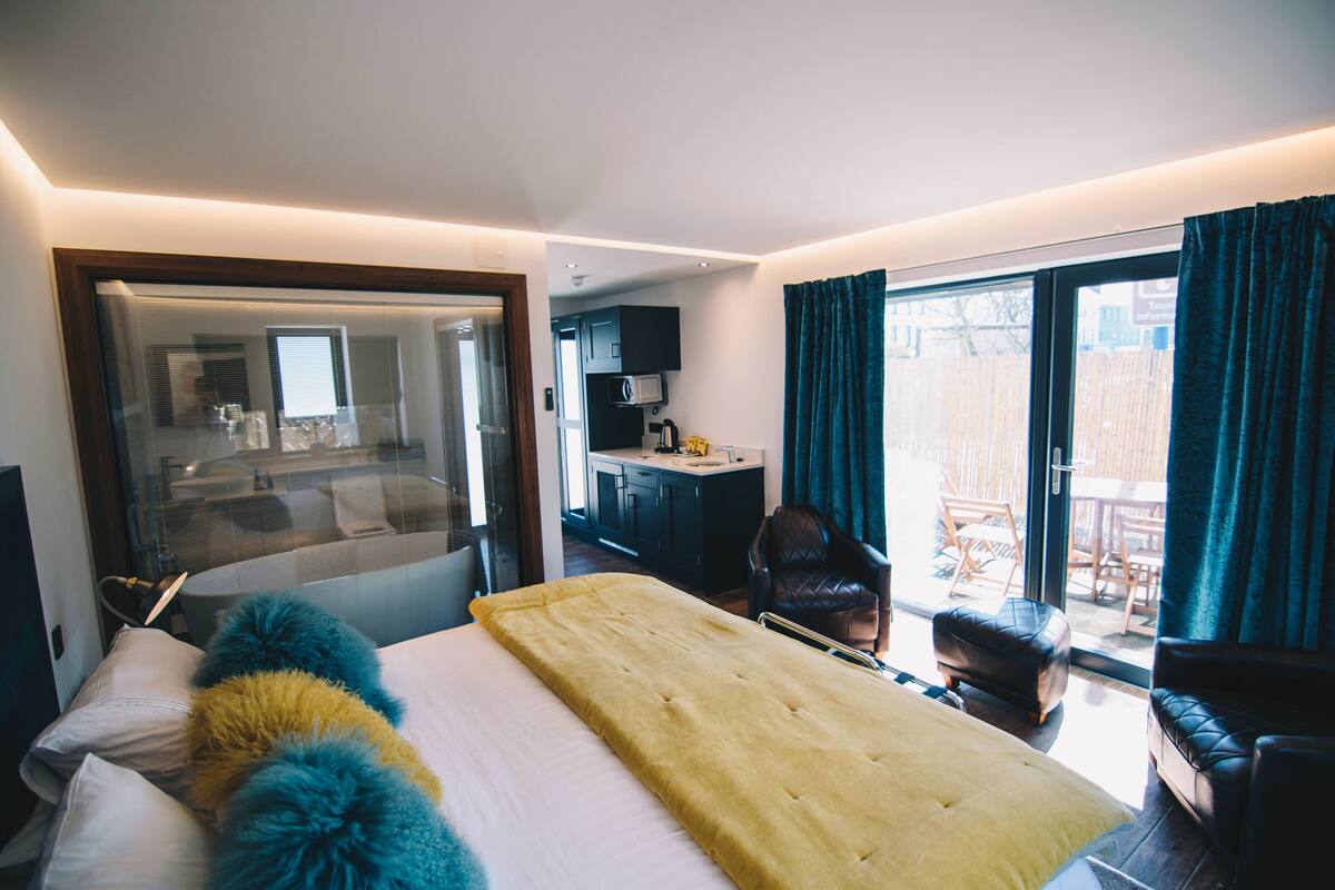 Une chambre d’hôtel avec un lit, un bureau, une chaise et une vue sur l’extérieur.