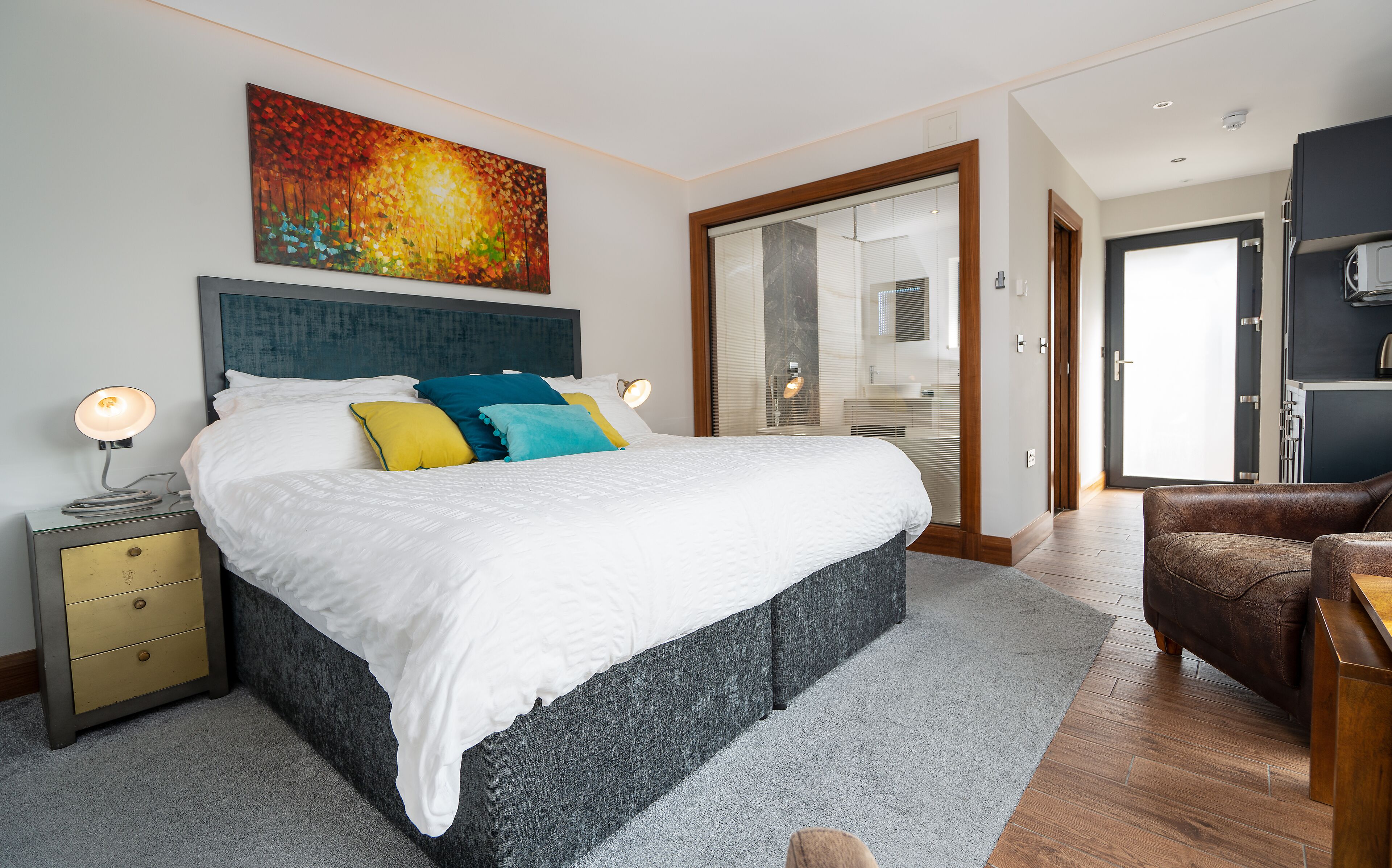 Un dormitorio moderno con una cama grande, mesita de noche y un cuadro sobre la cama.