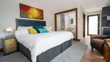 Un dormitorio moderno con una cama grande, mesita de noche y un cuadro sobre la cama.