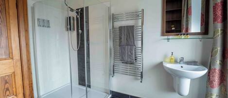 Un bagno moderno con box doccia in vetro, un porta asciugamani, un lavandino con specchio e una porta con cornice in legno.