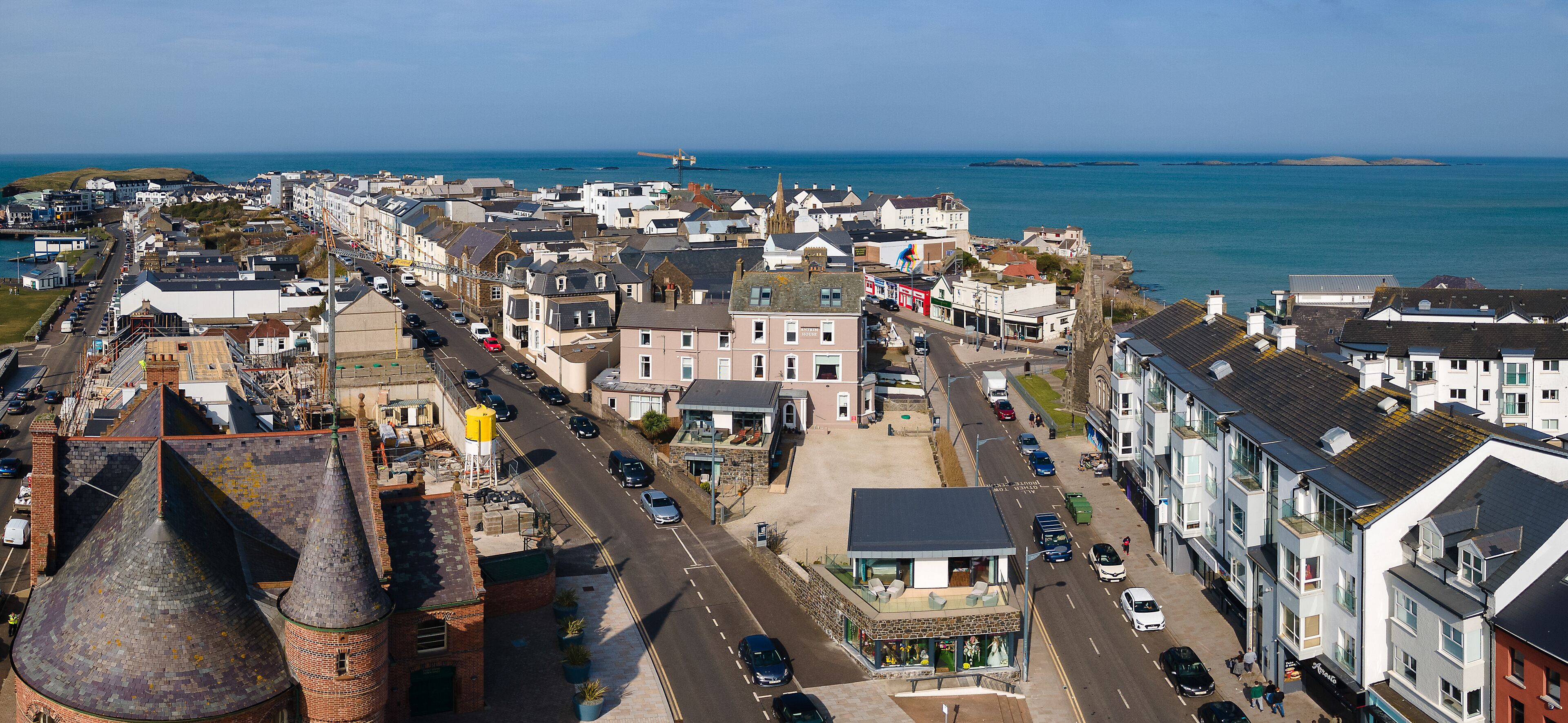A coastal town with historic buildings, a prominent tower, and a waterfront promenade.