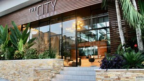 A modern hotel entrance with a stone facade, glass doors, and outdoor seating. - Beautiful Menesse the city, Delux Apartment (Playa del Carmen)