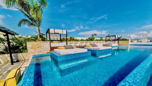 A swimming pool with lounge chairs and a stone wall. - Beautiful Menesse the city, Delux Apartment (Playa del Carmen)