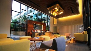 A modern lobby with yellow sofas, a reception desk, and large windows offering views of the outside. - Beautiful Menesse the city, Delux Apartment (Playa del Carmen)
