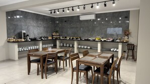 A modern kitchen with a marble backsplash, a coffee station, and a dining area with wooden tables and chairs. - Asa Hotel (Piracicaba)