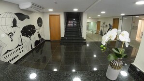 A lobby with a polished black floor, a staircase, and a wall with black and white artwork. - Asa Hotel (Piracicaba)