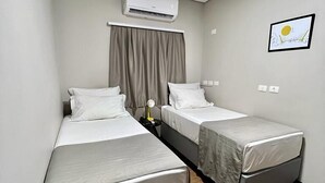 A small hotel room with two single beds, an air conditioning unit, a ceiling light, and a framed picture on the wall. - Asa Hotel (Piracicaba)