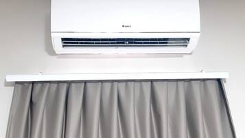 A white air conditioning unit mounted on a wall above a grey curtain.