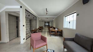 A spacious room with a dining area, a sofa, and a partition wall. - Asa Hotel (Piracicaba)
