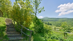A set of wooden stairs leading up a grassy hill with a view of a valley and hills in the distance. - Casa dell'Ambasciatore (Castiglione d'Orcia)